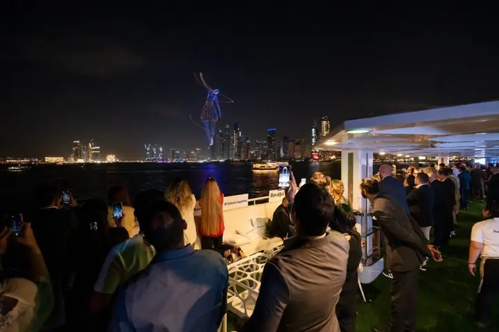 Guests on the yacht deck watch a drone show over the Dubai Marina skyline